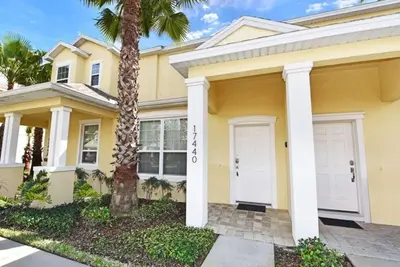 a yellow house with a palm tree in front of it at Beautiful 3-Bed Villa 10 Minutes From Disney - Serenity Resort townhouse in Orlando