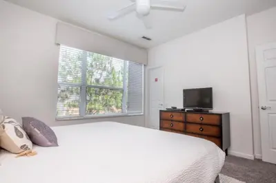 a white bedroom with a bed and a television at Vista Cay Casa Bonita townhouse in Orlando