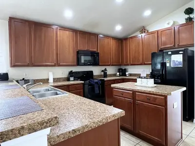 a kitchen with wooden cabinets and a black refrigerator at Cozy 4 Bed 3 Bath Private Pool Home with Game Room home in Kissimmee