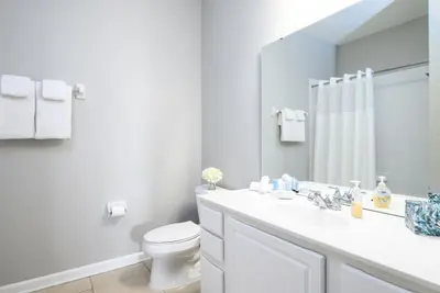 a bathroom with a sink and a toilet and a mirror at Vista Cay Lakeview Elysium condo in Orlando