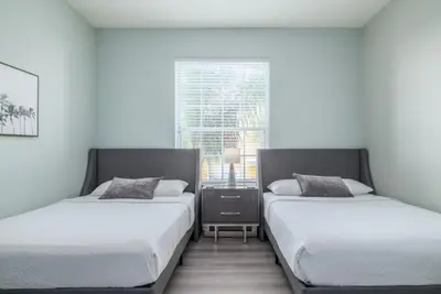 two beds in a white room with a window at Vista Cay Lakeview Elysium condo in Orlando
