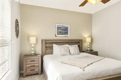 a white bedroom with a bed and two night stands at Vista Cay Luxury Secret condo in Orlando