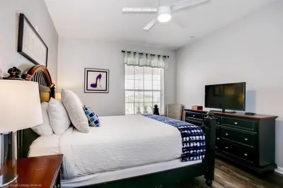a bedroom with a bed with a dresser and a television at Lake View 3 Bedroom In Vista Cay Resort condo in Orlando
