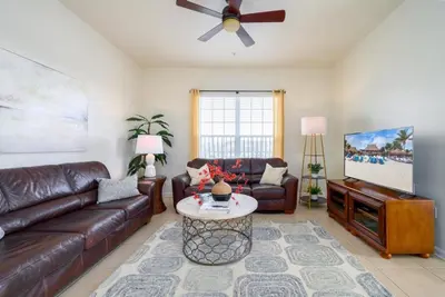 a living room with a leather couch and a tv at Pool View Penthouse condo in Orlando