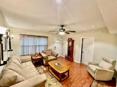 a living room with a couch and chairs and a clock at Cozy Modest Home near Universal Studios/VolcanoBay in Orlando