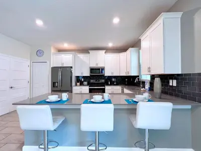 a large kitchen with white cabinets and white chairs at Spacious Home with Fun Decore and Game Room-4544TB in Kissimmee