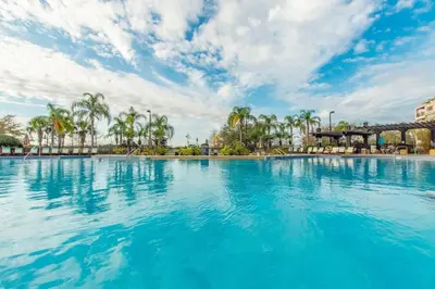 a large swimming pool with blue water and palm trees at Vista Cay Luxury Loft in Orlando