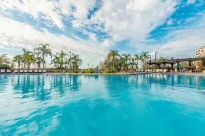 a large swimming pool with blue water and palm trees at Vista Cay - Cosy 3 bedroom condo in Orlando