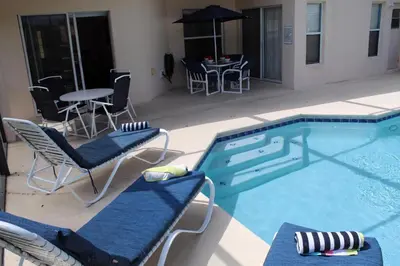 a swimming pool with chairs and a table and a table and chairs at Emerald Escape - New Pool Home in Kissimmee