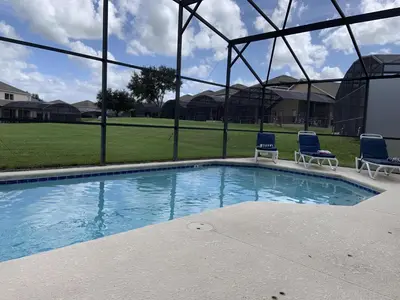 a swimming pool with two blue chairs and aermottermott at Emerald Escape - New Pool Home in Kissimmee