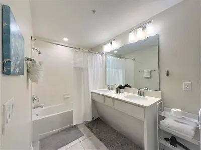 a white bathroom with a tub and a sink and a bath tub at Charming Holiday Condo, Only 7 min to Disney in Kissimmee