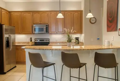 a kitchen with a counter with three bar stools at Vista Cay Luxury 3BR Condo in Orlando