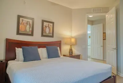 a bedroom with a large bed with blue pillows at Luxury Lake View Condo-Vista Cay in Orlando