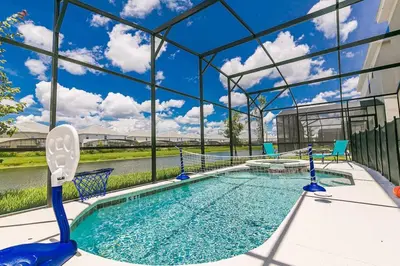 a swimming pool with blue chairs in a building at ☀️12BR Disney Villa Paradise w/ Game Room & Pool/Spa☀️ in Kissimmee