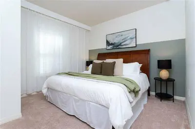 a bedroom with a large bed with white sheets and pillows at Modern Family-Friendly Townhome – 10 Min Parks in Kissimmee