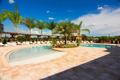 a pool at a resort with palm trees and chairs at Modern Family-Friendly Townhome – 10 Min Parks in Kissimmee