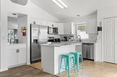 a kitchen with white cabinets and two blue stools at Amazing Pool Spacious 3BR House near Disney in Kissimmee