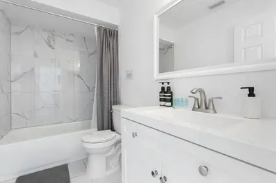 a white bathroom with a toilet and a sink at Amazing Pool Spacious 3BR House near Disney in Kissimmee