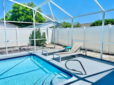 a swimming pool with a chair and a table at Amazing Blue Private Pool 4BR House Near Disney in Kissimmee