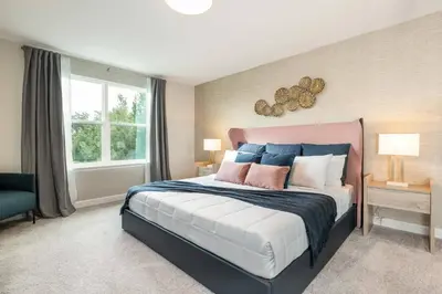 a bedroom with a large bed with blue and pink pillows at 7992 Cozy 5BD Disney Getaway with Pool in Orlando
