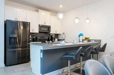 a kitchen with a refrigerator and a counter with chairs at Gorgeous 4 Bd w Pool at Storey Lake Resort 4277 in Kissimmee