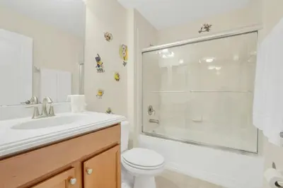 a white bathroom with a toilet and a shower at Near Disney - 5BR Home- Games Pool Hot Tub & BBQ in Kissimmee