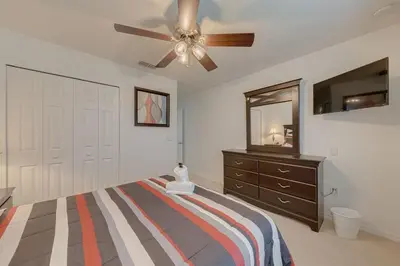 a bedroom with a bed with a ceiling fan and a dresser at 558 - Veranda Palms House in Kissimmee
