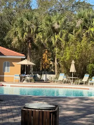 a pool with chairs and umbrellas next to a house at Vacation Home for 8, near Disney and Universal in Kissimmee