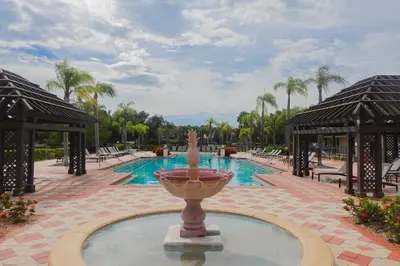 a fountain in the middle of a pool at a resort at Summer Fun - Waterfront 8BR Home with Private Pool! in Kissimmee