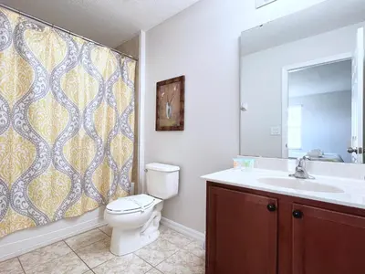 a bathroom with a toilet and a sink and a mirror at Beautiful 6Bd Pool Hm Veranda Palms-4464NP in Kissimmee