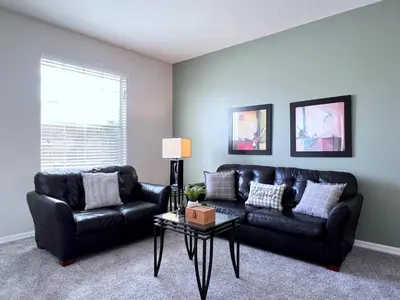 a living room with a black leather couch and a table at Beautiful 6Bd Pool Hm Veranda Palms-4464NP in Kissimmee