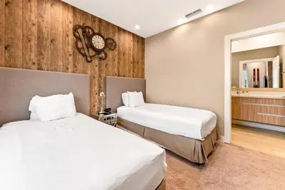 a bedroom with two beds and a clock on the wall at 7594 Magic Village 3suites 6guets 8 min Disney in Orlando