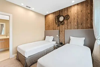 two beds in a room with a clock on the wall at 3081 Magic Village 4suites Jacuzzi Near 192 8 min Disney in Orlando