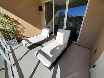 two white lounge chairs on the balcony of a house at 7659 Magic Village Excellent 4 suites 6 min Disney in Orlando