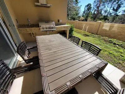 a patio with a table and two chairs and a grill at 7659 Magic Village Excellent 4 suites 6 min Disney in Orlando