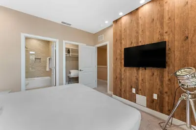 a bedroom with a bed and a tv on a wall at 7564 Magic Village 3 suites jacuzzi BBQ 8 min Disney in Orlando
