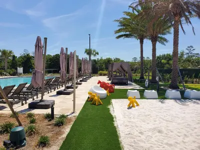 a resort with a beach with chairs and a pool at 3053 Magic Village 3 suites jacuzzi BBQ 6min Disney in Orlando
