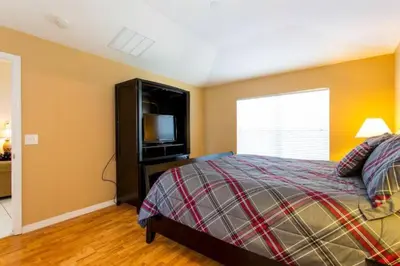 a bedroom with a bed and a tv and a window at Eva Kingdom back to forest home close to disney in Kissimmee