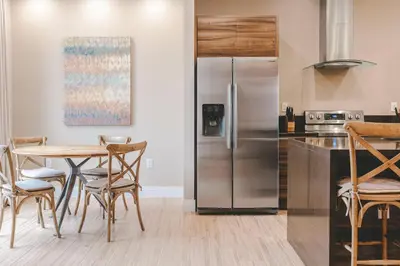 a kitchen with a table and a stainless steel refrigerator at 7478 Magic Village 8guests 4suites 8min Disney in Orlando