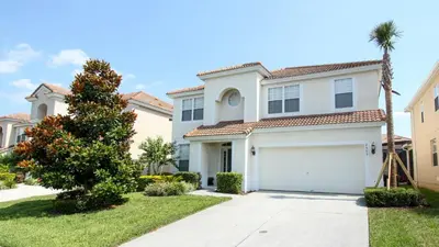 a white house with a garage and a palm tree at 2505 Archfeld in Kissimmee