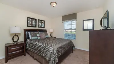 a bedroom with a bed and a dresser and a television at 3031 Beach Palm in Kissimmee