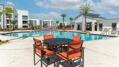 a black table with orange chairs next to a swimming pool at 4741 Clock Tower #102 in Kissimmee