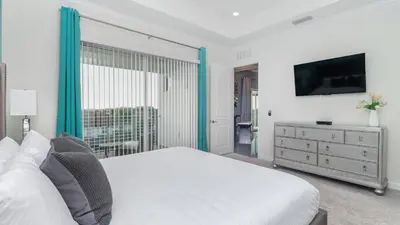 a white bedroom with a bed and a television at 4751 Clock Tower #401 in Kissimmee