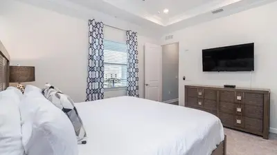 a bedroom with a large bed and a flat screen tv at 4751 Clock Tower #401 in Kissimmee