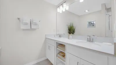 a white bathroom with two sinks and a mirror at 3111 Paradox #202 in Kissimmee