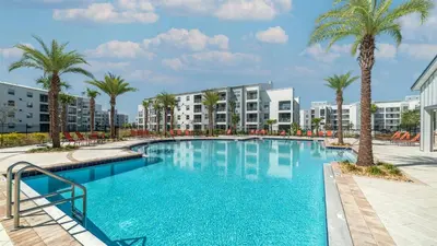 a large swimming pool with palm trees and buildings at 3151 Paradox #102 in Kissimmee