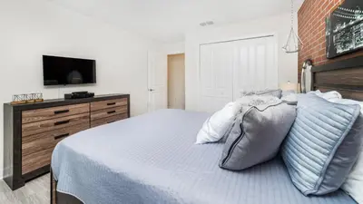 a white bedroom with a bed and a tv at 4951 Windermere in Kissimmee