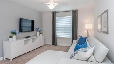 a white living room with a white couch and a tv at 4741 Kings Castle C in Kissimmee