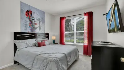 a bedroom with a bed and a window with red curtains at 7739 Comrow in Kissimmee