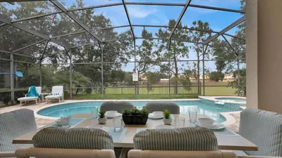 a dining table and chairs in front of a swimming pool at 7739 Comrow in Kissimmee